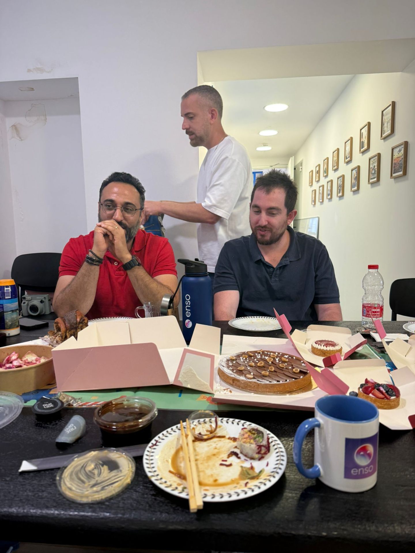 Team gathered around a table full of cakes and food