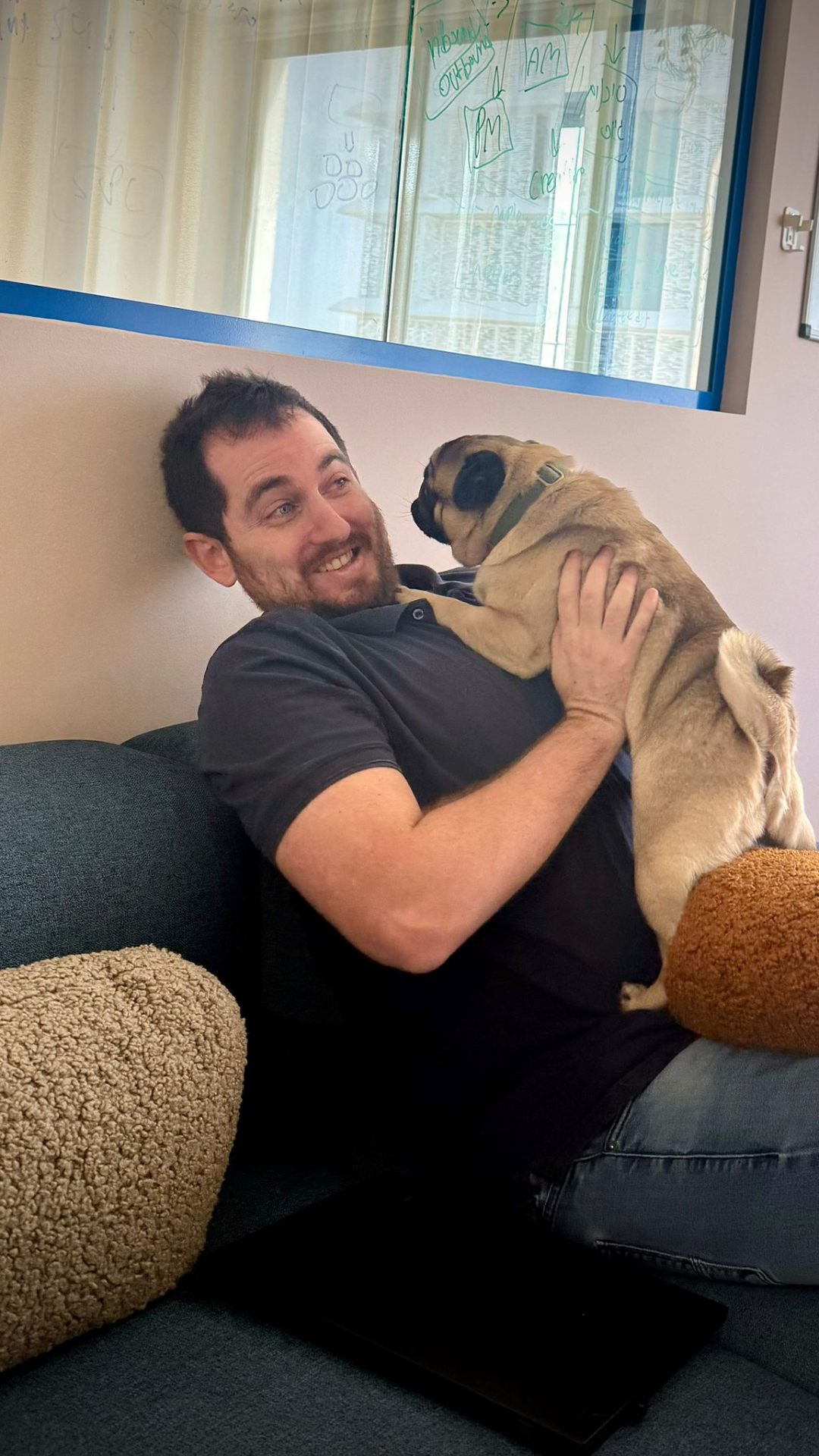Team member hugging a pug on the office couch